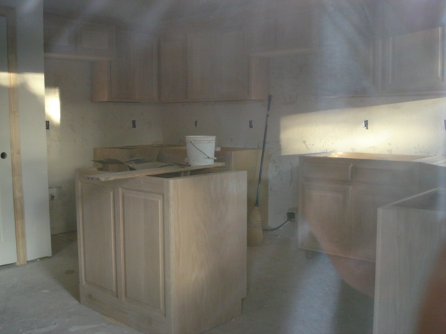 Kitchen under construction with unfinished cabinets and a bucket