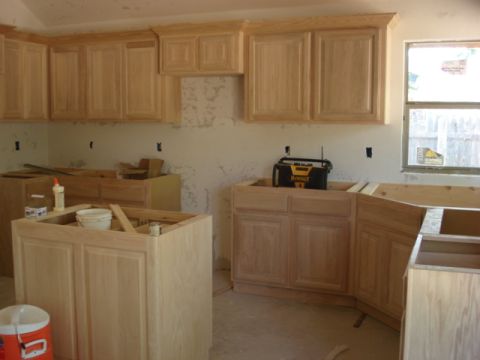 1994 Ford Bronco - A kitchen renovation is underway with unfinished wooden cabinets and a window overlooking a fence.