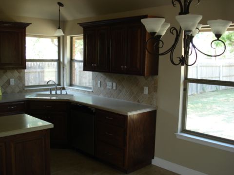 1994 Ford Bronco - Interior view of a kitchen dark wood cabinetry, a corner sink, and a window with a view of the backyard.