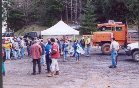1976 Ford F-100 - People stand around a large orange truck and other vehicles in an outdoor gathering.