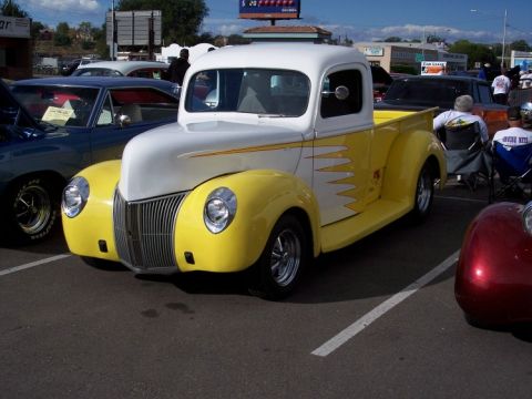 1972 Ford Ranchero - A classic yellow and white pickup truck with custom flame decals is parked at a car show.