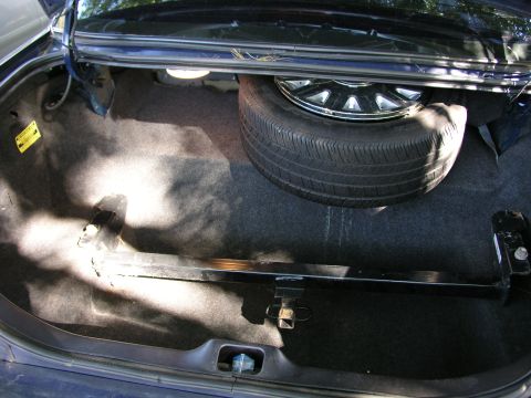 1999 Ford Crown Victoria - Trunk interior of a 1999 Ford Crown Victoria, complete with spare tire and jack components.