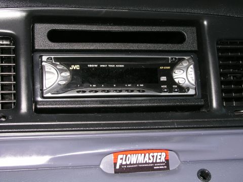 1999 Ford Crown Victoria - A close-up view of a car's dashboard, an aftermarket JVC stereo system and a Flowmaster sticker.
