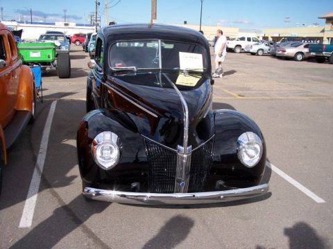 1972 Ford Ranchero - A black classic car from the 1940s is parked at a car show, its chrome details gleaming in the sun.