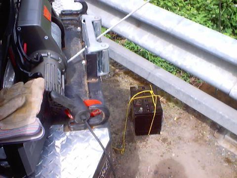 1976 Ford F-100 - A battery and winch are shown outdoors next to a metal guardrail.
