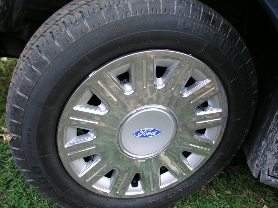 Close-up of a chrome Ford wheel cover with a blue Ford logo on a tire