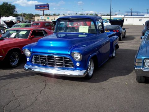 1972 Ford Ranchero - A bright blue pickup truck is parked at a car show, displaying its polished chrome grille and custom hood.