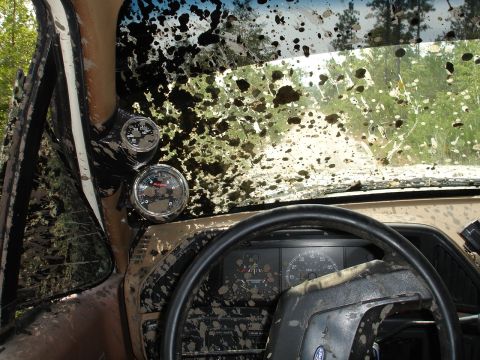 1989 Ford Bronco - The interior of a vehicle is covered in mud, with the windshield heavily splattered.