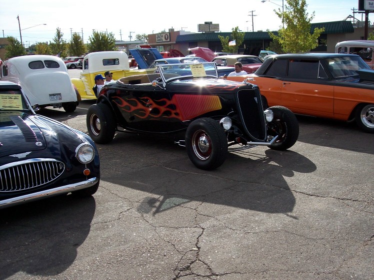 Black hot rod with orange and yellow flames on the side, viewed from a 3/4 front angle