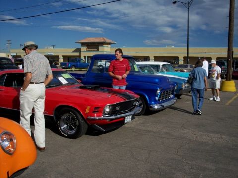 1972 Ford Ranchero - A red muscle car with black stripes is displayed at a car show with other vehicles.