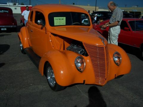 1972 Ford Ranchero - An orange hot rod coupe is displayed at a car show with its hood open, revealing the engine.