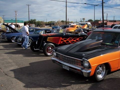 1972 Ford Ranchero - A row of custom cars, including a black and orange 1966 Chevrolet Nova, are displayed at an outdoor event.