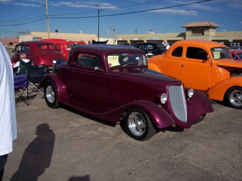1972 Ford Ranchero - A custom maroon coupe hot rod is displayed at a car show, with other vehicles visible in the background.