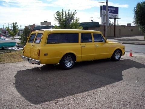 1972 Ford Ranchero - A bright yellow station wagon is parked on an asphalt lot, casting a long shadow.