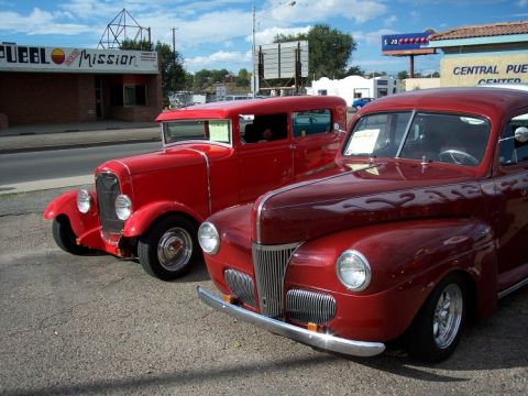 1972 Ford Ranchero - Two classic red hot rod cars are parked next to each other on a sunny day.