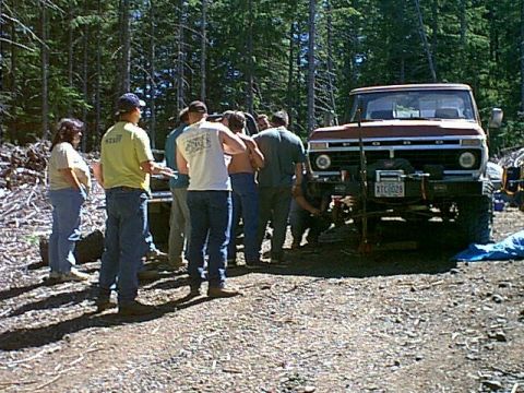 1976 Ford F-100 - A group of people gather around a red 1976 Ford F-100 truck, which features a winch mounted on the front.