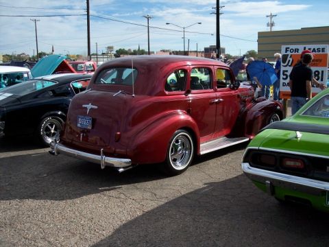 1972 Ford Ranchero - A red sedan is parked at a car show next to other vehicles.