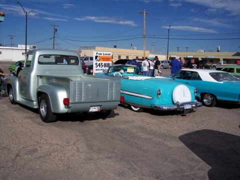 1972 Ford Ranchero - A silver 1955 Ford F-100 pickup truck is parked alongside two turquoise classic cars at a car show.