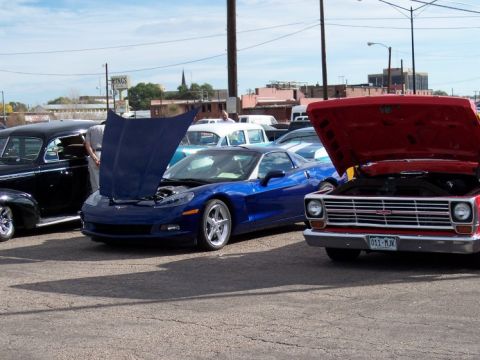 1972 Ford Ranchero - A blue sports car is parked at a car show with its hood open, alongside other vehicles.