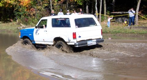 1979 Ford Bronco - This Ford Bronco navigates a muddy trail, kicking up water as it goes.