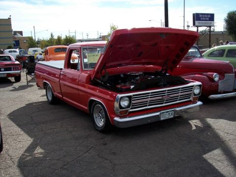 1972 Ford Ranchero - A red pickup truck is displayed with its hood open, parked alongside other vehicles at an outdoor event.