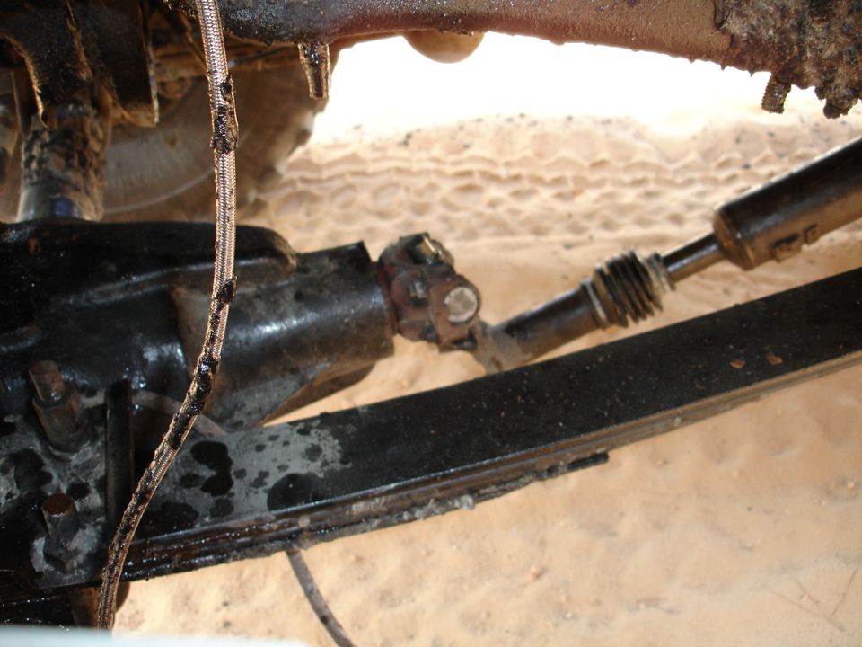 Underside of a vehicle showing a U-joint, driveshaft, and leaf spring
