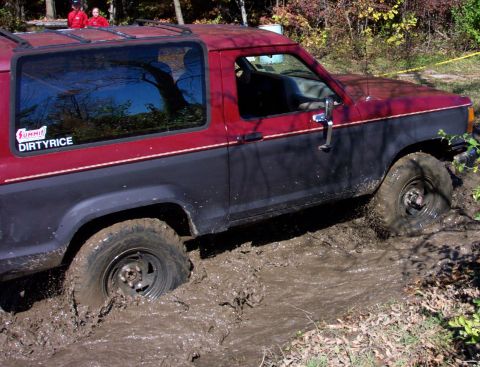 1979 Ford Bronco - This red and blue 4x4 is deep in the mud, showing its off-road capabilities.