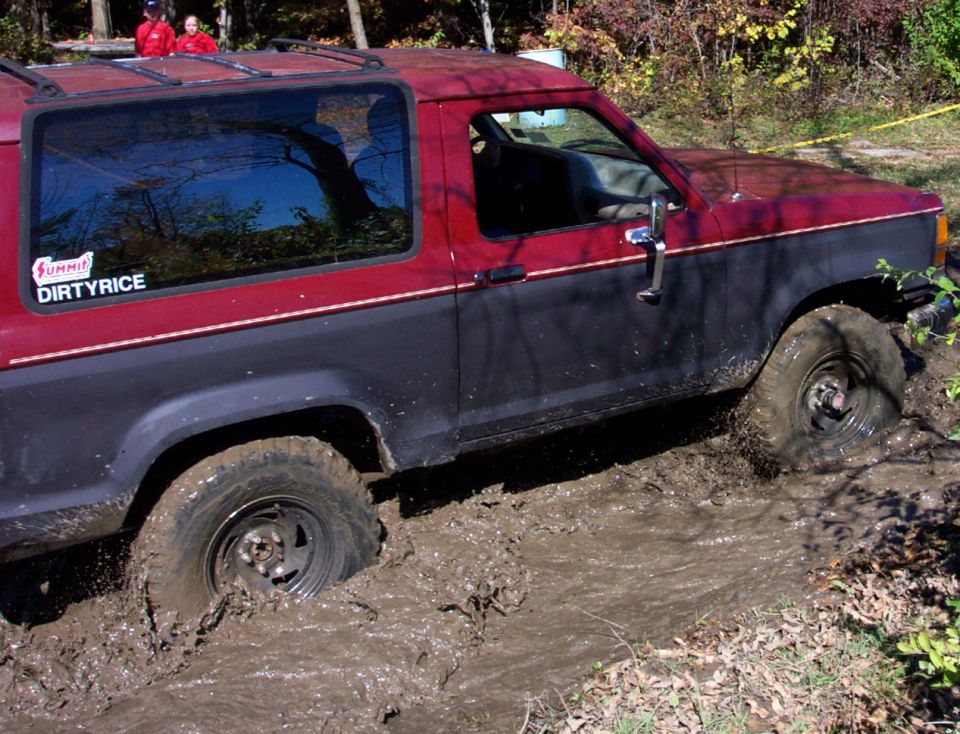 Red and blue 4x4 stuck in mud, side view