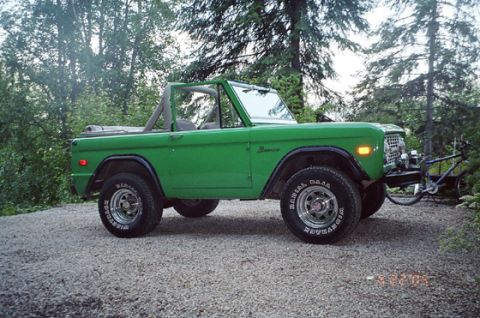 1975 Ford Bronco - A green 1975 Ford Bronco is parked outdoors with a bicycle rack attached to its front bumper.