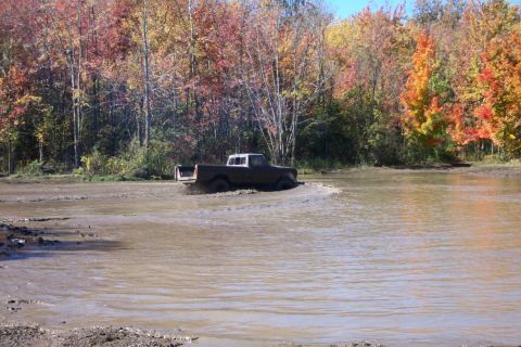 1979 Ford Bronco - Pickup truck navigates a muddy terrain during autumn.