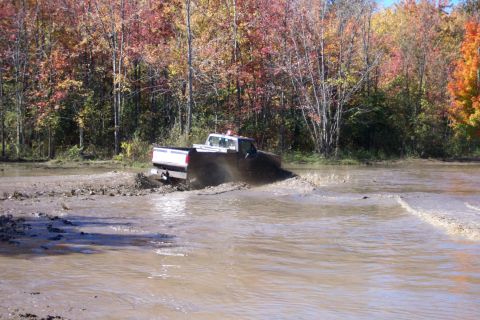 1979 Ford Bronco - A truck navigates through a muddy terrain, kicking up water and mud.