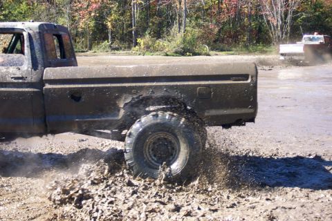 1979 Ford Bronco - A Ford pickup truck navigates a muddy track, with another vehicle visible in the background.