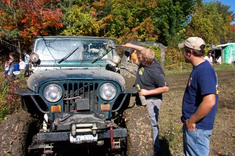 1979 Ford Bronco - Two men observe a mud-covered Jeep Wrangler, with another off-road vehicle visible in the background.
