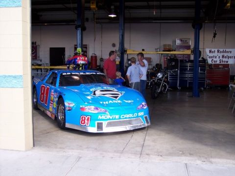 1972 Ford Ranchero - A blue race car with the number 81 and 'Monte Carlo SS' branding is parked inside a garage.