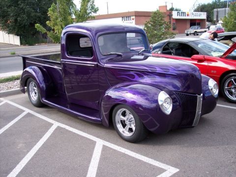 1972 Ford Ranchero - A custom purple pickup truck with flame decals is parked next to a red sports car.