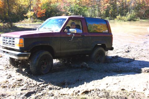 1979 Ford Bronco - Ford Bronco navigating a muddy off-road trail during autumn.