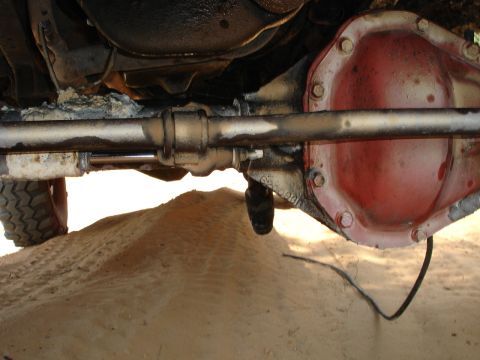 1989 Ford Bronco - Close-up of the rear axle and suspension parts of a vehicle, showing the differential cover and related components.