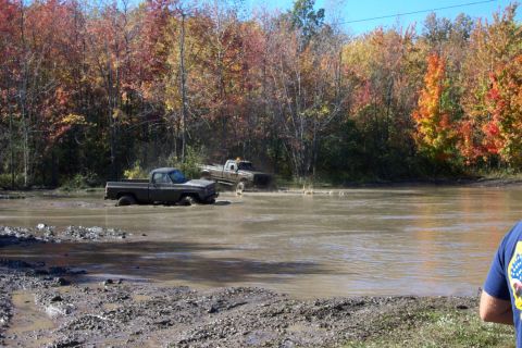 1979 Ford Bronco - Two trucks are stuck in a muddy water hole during the fall season.