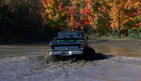 1979 Ford Bronco - A black Ford pickup truck navigates a muddy path during autumn.