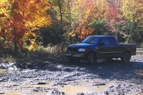 1979 Ford Bronco - Pickup truck navigating a muddy terrain during autumn.