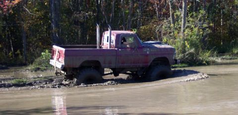 1979 Ford Bronco - This pickup truck is stuck in the mud, with its tires submerged in water and mud.