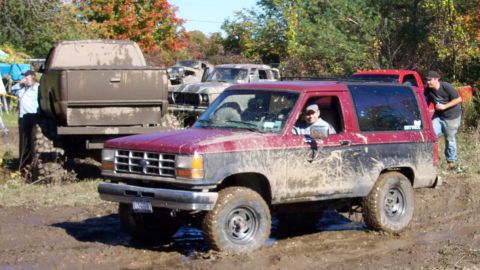 1979 Ford Bronco - Several muddy trucks are stuck in the mud during an off-road event.