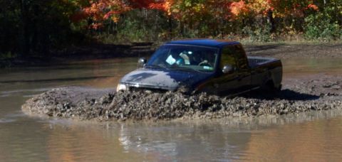 1979 Ford Bronco - Pickup truck struggling through a muddy water obstacle during an off-road excursion.