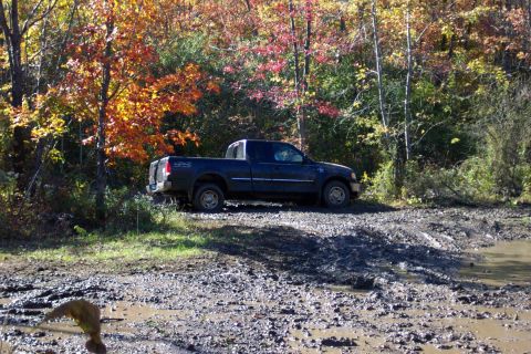 1979 Ford Bronco - Pickup truck on a muddy trail during autumn.