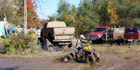 1979 Ford Bronco - Multiple vehicles are engaged in off-roading activities in a muddy terrain with trees in the background.