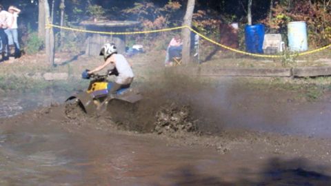 1979 Ford Bronco - An ATV navigates a muddy track, kicking up a large spray of dirt.