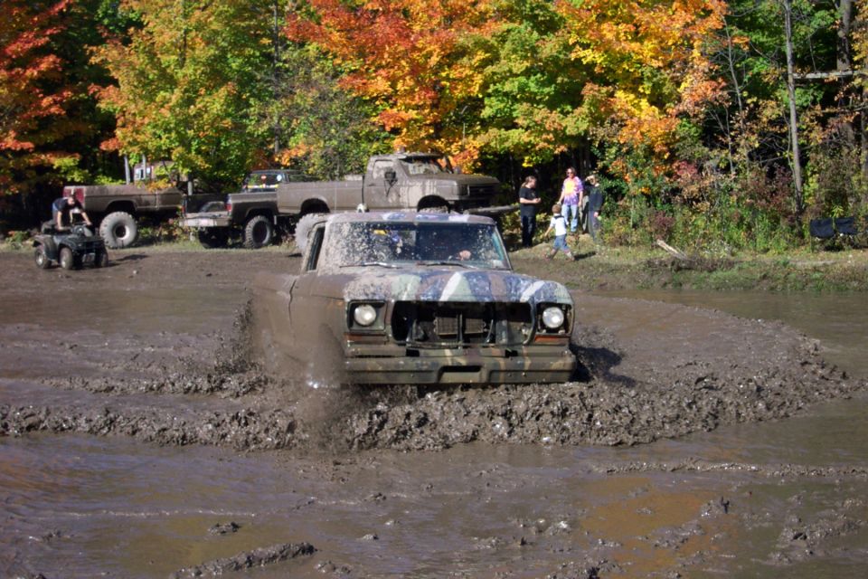 Mud-splattered 1979 pickup truck driving through mud pit
