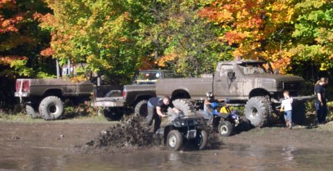1979 Ford Bronco - Off-roading fun with trucks and ATVs in a muddy, wooded area during autumn.