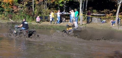 1979 Ford Bronco - ATVs navigate a challenging muddy course as onlookers observe the action.