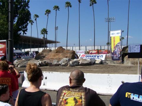 1995 Ford Bronco - Spectators gather to watch an off-road event with banners and a grandstand in the background.